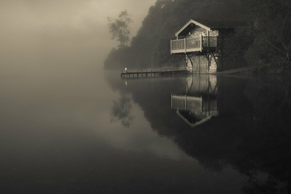 Lago nella nebbia con una casa solitaria