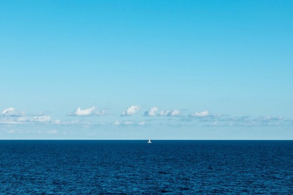 La vela solitaria diventa bianca nella nebbia blu del mare