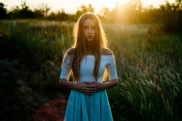 La ragazza nel prato è illuminata dai raggi del sole